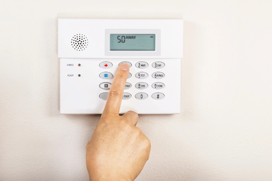 homeowner setting a home alarm system that is mounted on the wall